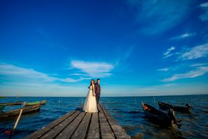 Coastal wedding scene with wooden dock leading to horizon over tranquil waters.