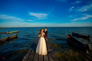 Panoramic view of a wedding photoshoot on a rustic dock extending into calm blue waters.
