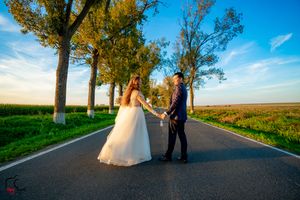 A couple poses on a scenic country road with rows of trees during their wedding day.