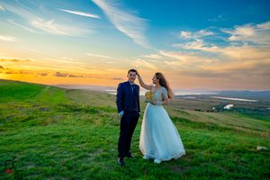 Sunset wedding photography with couple silhouetted against golden sky on rolling hills.