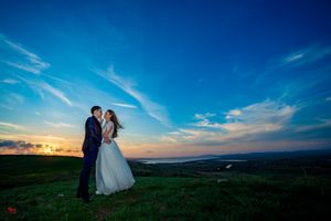 Romantic hilltop wedding portrait with expansive views of countryside at dusk.