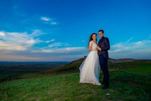 Romantic sunset wedding photography session on grassy hilltop with panoramic countryside views.