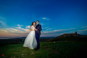 Elegant wedding photo taken on scenic overlook with sweeping landscape views at sunset.