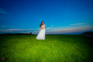 Wedding couple photographed in wide landscape shot with vibrant green meadow.