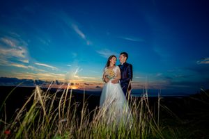 Wedding couple embraces on scenic mountain overlook during blue hour.