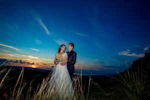 Elegant wedding portrait with dramatic mountain landscape at sunset.