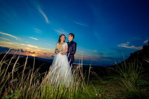 Romantic sunset wedding portrait with mountains and tall grass in background.