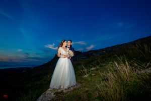 Elegant wedding portrait captured against majestic mountain scenery at dusk.