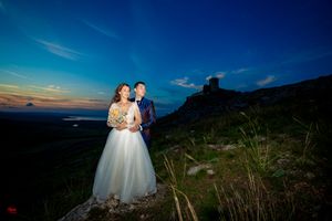 Wedding portrait with dramatic blue hour lighting and mountain castle silhouette.