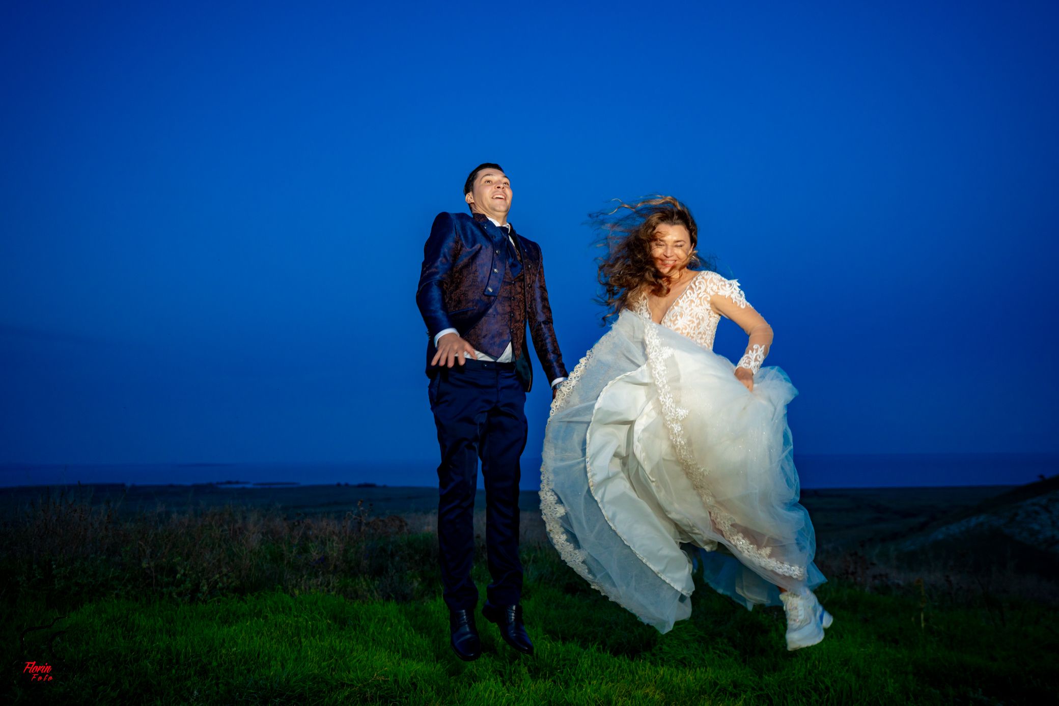 Romantic outdoor wedding portraits with dramatic blue sky and rolling hills in background.