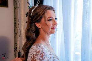 Ethereal bridal portrait against window light showing intricate lace wedding dress details.