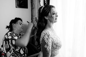 Side profile of a bride getting ready, wearing an elegant lace-adorned wedding dress.