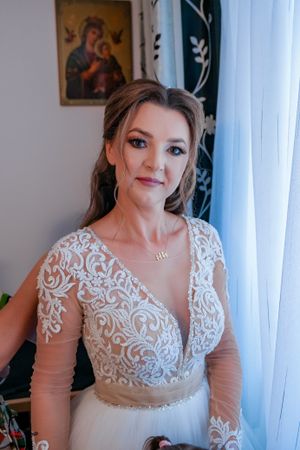 Romantic bridal portrait highlighting delicate lace patterns on a white wedding gown with sheer details.