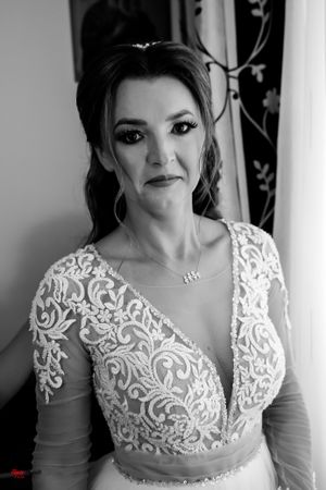Monochrome portrait of a bride in an intricately detailed wedding dress with mesh and lace elements.
