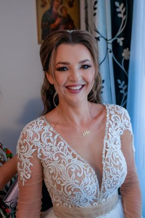 Candid bridal portrait featuring an ornate white lace wedding dress with long sheer sleeves.
