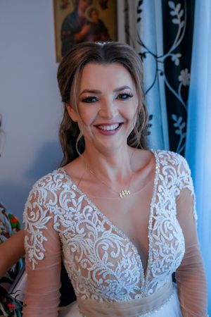 Joyful bridal portrait showing detailed white lace appliques on a sheer-sleeved wedding gown.
