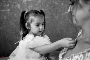 A black and white portrait capturing a gentle family interaction against textured wall.