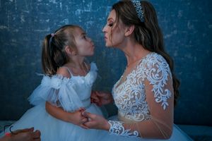 An intimate family moment captured against a deep blue backdrop with delicate lace details.