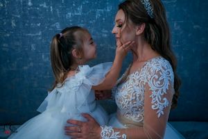 A touching family portrait showing affection between parent and child in front of a blue wall.