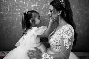 A tender black and white portrait showing a sweet moment between parent and child against a textured wall.