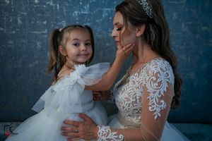 Candid wedding portrait showing affectionate interaction between two in coordinating white dresses.