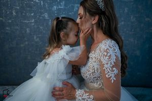 Sweet candid moment during a wedding photoshoot featuring elegant white dresses and delicate details.
