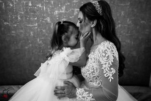 Black and white photo capturing a tender moment between two in matching white dresses.