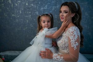 Intimate wedding portrait featuring delicate lace and tulle dresses against a moody blue background.