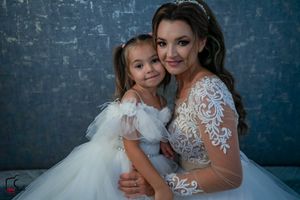 Beautiful portrait showcasing the intricate lace details of a wedding dress alongside a fluffy tulle flower girl dress.