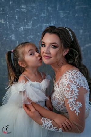 Heartwarming wedding photo of bride and flower girl sharing an affectionate moment.