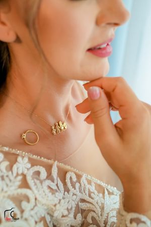 Close-up of intricate lace wedding dress neckline and dainty gold jewelry.