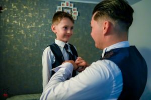 Formal gathering showing interaction between two people near a decorated wall.