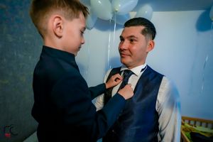 A sweet moment of tie adjustment captured during formal event preparations.