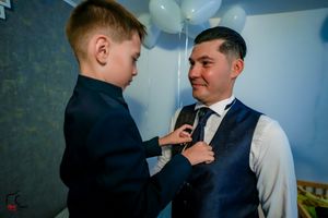 An endearing scene of formal wear preparation with white balloons in the background.