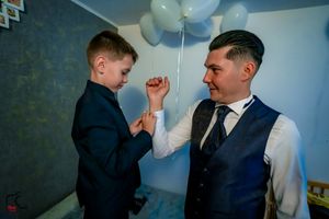 A joyful interaction captured in a room decorated with pastel blue balloons and formal attire.