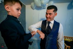 Two people share a special moment in formal wear at a celebration with blue and white balloons.