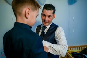 A touching moment captured between two people in formal attire with blue balloons in the background.