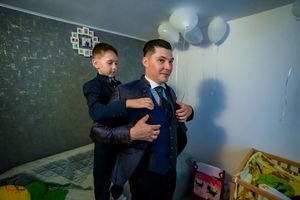 Two people share a playful moment in a room decorated with light blue balloons.