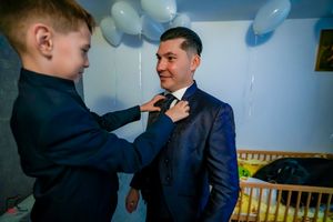Two people in suits share a candid moment at a celebration with balloons.