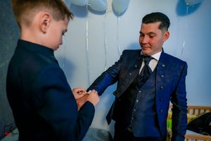 Two people in matching dark suits interact playfully at a formal event.