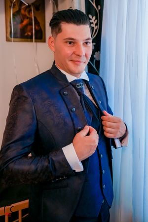 Person in a navy blue suit adjusts their tie while getting ready.