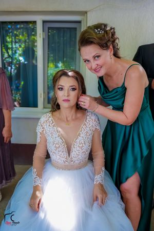 A stunning white wedding gown with intricate lace details and full tulle skirt being prepared for the ceremony.