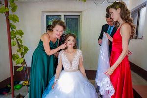 Bridal preparation scene showing attendants helping with final details before the ceremony.