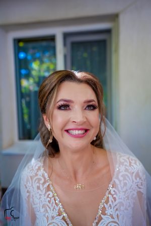 Close-up portrait of a bride in a white lace wedding dress and veil smiling at the camera.