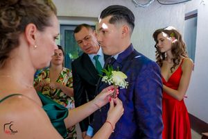 Group of wedding attendants assisting with formal wear preparations before the ceremony.