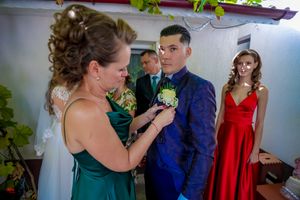 Wedding party members in emerald green and navy blue attire gathered in an indoor setting.