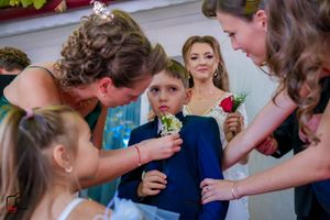 Candid wedding preparation moment showing attire adjustments between wedding party members.
