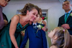 A tender moment at a wedding with a person in teal adjusting a young attendant's boutonniere.