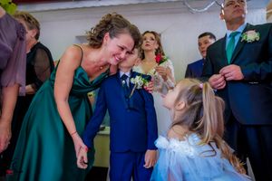 Wedding guests mingle during a reception with greenery decorations visible.