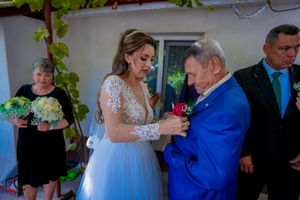 Wedding party members interact during a reception with decorative green vines visible in the background.